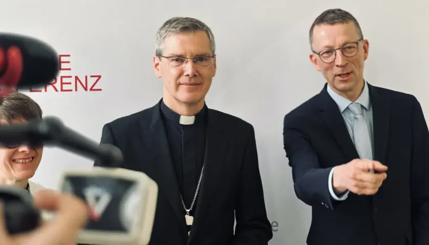 Der Vorsitzende der Deutschen Bischofskonferenz, Georg Bätzing, im Gespräch mit einem Mann im Anzug.