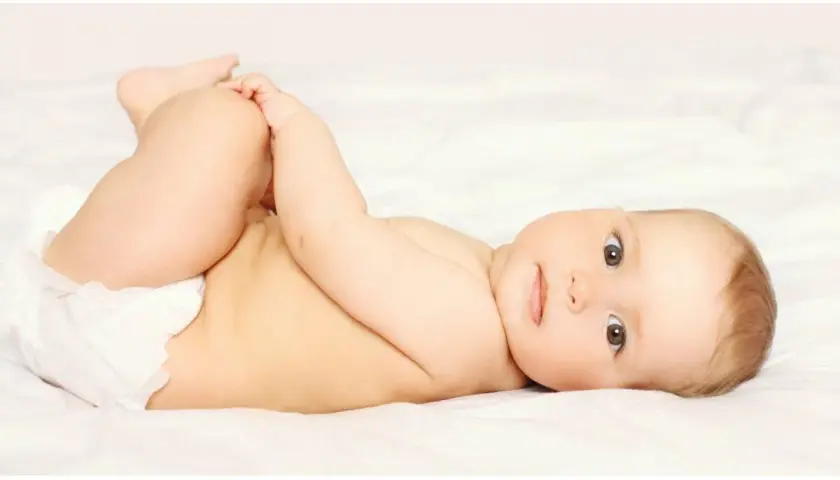 Bambino con pannolino, gambe sollevate, pronto per un cambio per prevenire la candida da pannolino.