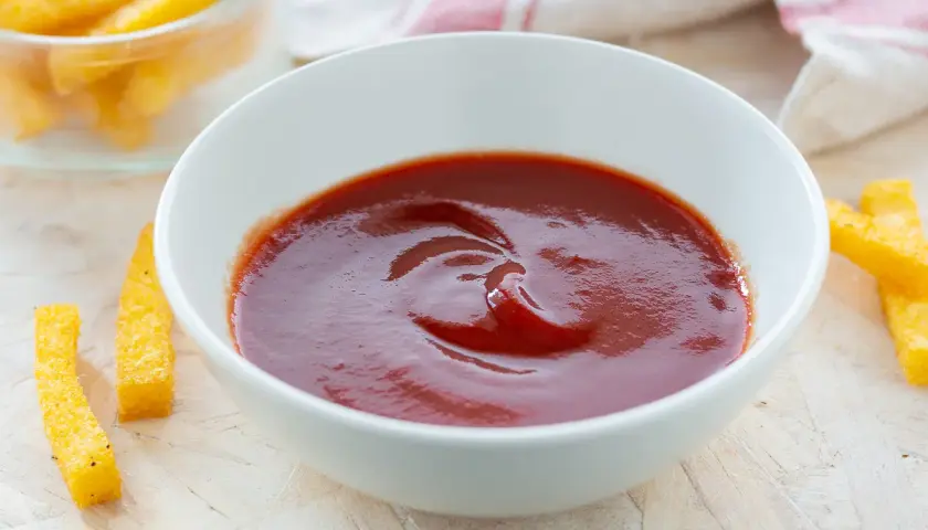Ciotola di ketchup fatto in casa, con bastoncini di polenta fritta intorno.