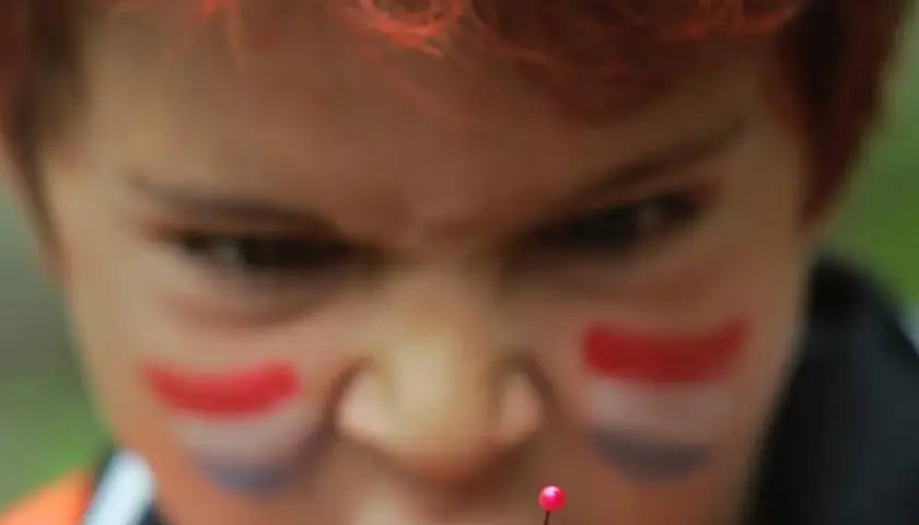 Niño con pintura facial de bandera, con mirada intensa, como si temiera el mal de ojo.