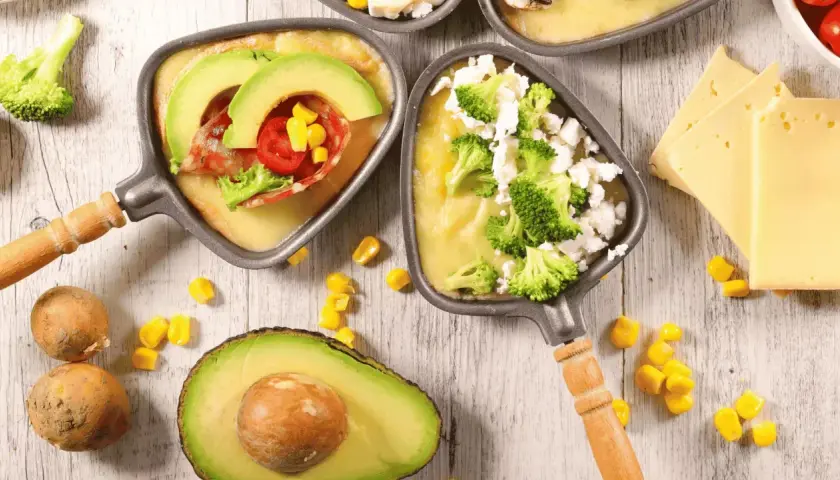 Poêlons de raclette végétarienne avec avocat, brocolis et maïs. Une option gourmande et colorée pour un repas convivial.