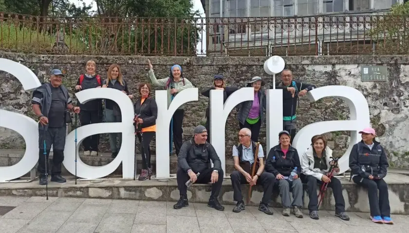 Grupo de peregrinos posa frente a las letras gigantes de Sarria, final de su **tren Santiago Sarria**.