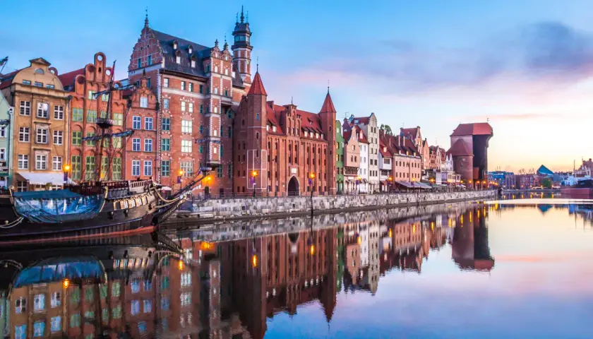 Zachód słońca nad Motławą w Gdańsku, z zabytkowymi kamieniczkami i żaglowcem. Idealne miejsce na podróż, gdy planujesz loty Wrocław Gdańsk.