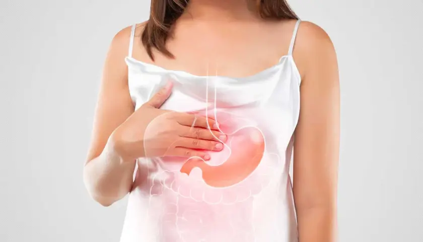 Donna con mano sullo stomaco, evidenziato da un'illustrazione luminosa. Simboleggia il bruciore di stomaco in gravidanza.