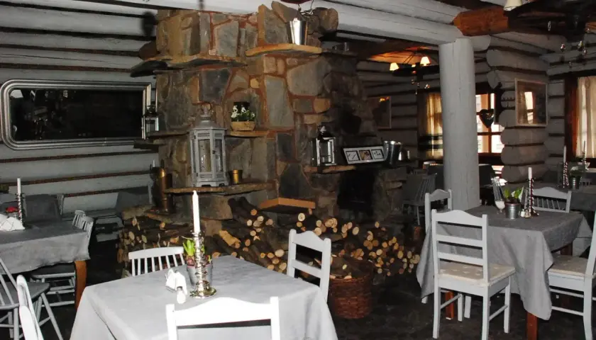Przytulne bistro prosto z targu, z kamiennym kominkiem i drewnianymi belkami. Stoły nakryte szarymi obrusami, białe krzesła.