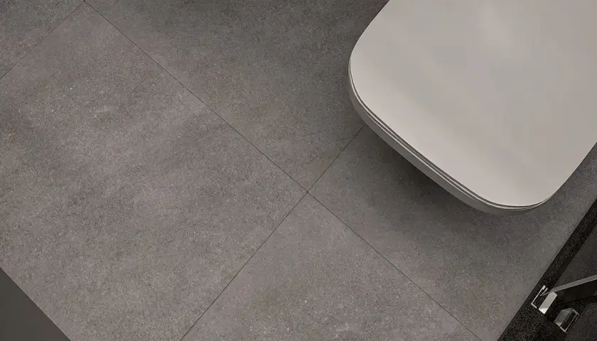 Nowoczesne wzory układania płytek 60x60 w łazience. Szare, wielkoformatowe płytki tworzą minimalistyczną bazę dla białej wanny.