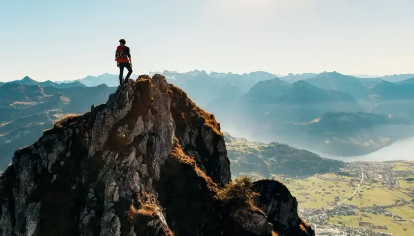 Alpinista na szczycie skalistej góry, podziwiający panoramę. Czy wejście na rysy jest trudne? Widok zapiera dech w piersiach, ale droga na górę wymaga wysiłku.