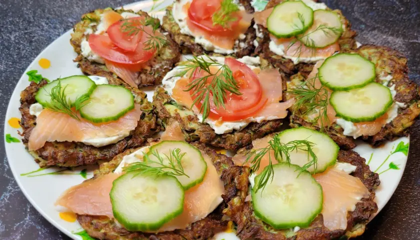 Placki z cukinii z łososiem, kremowym serkiem, pomidorem i ogórkiem, ozdobione koperkiem. Pyszna przekąska!