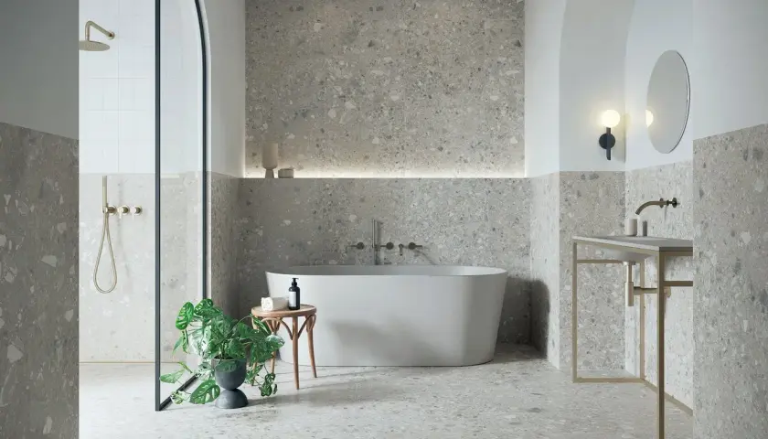 Modernes Badezimmer mit Terrazzo-Fliesen. Der Fliesentrend für Bäder zeigt sich hier in stilvoller Optik mit freistehender Wanne und Dusche.