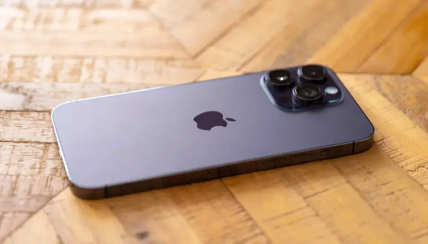 Nowy iPhone 14 Pro Max aparat z trzema obiektywami na drewnianym tle.