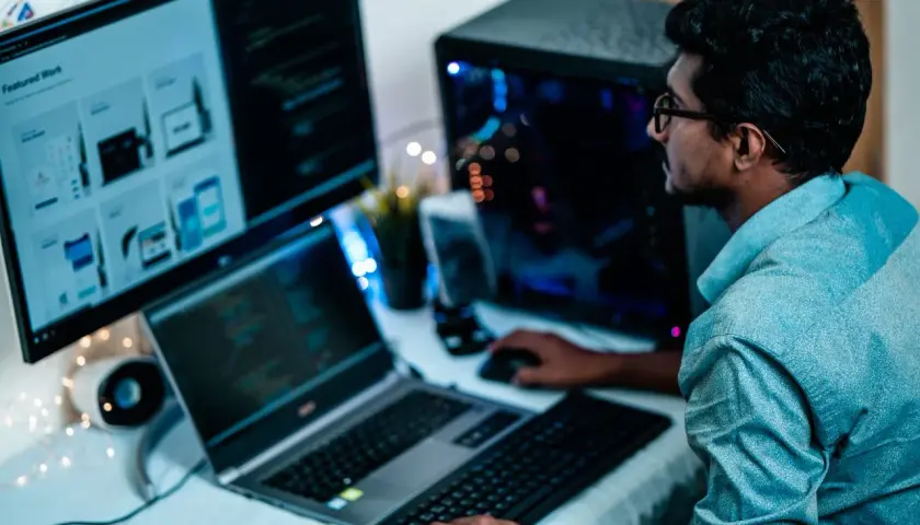 Un homme concentré sur ses écrans, le bon distance ecran yeux pour coder.