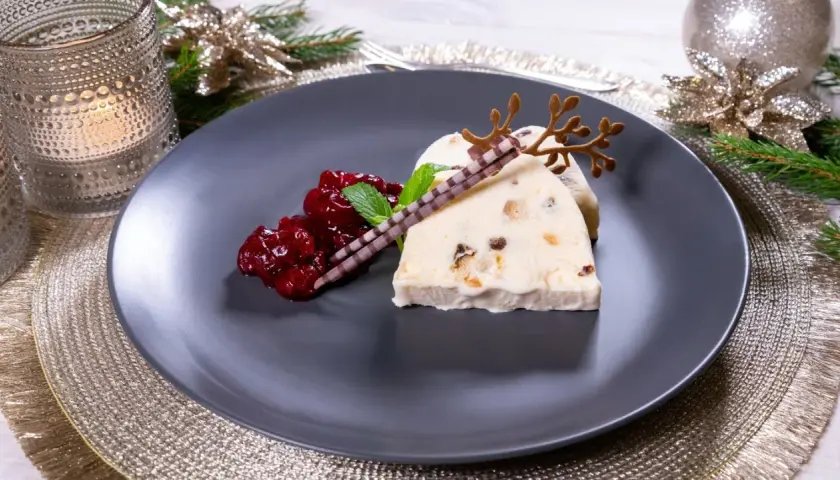 Ein festlicher weihnachts nachtisch: Eisparfait mit Beerenkompott, Schokoladenstäbchen und Rentiergeweih-Dekoration.