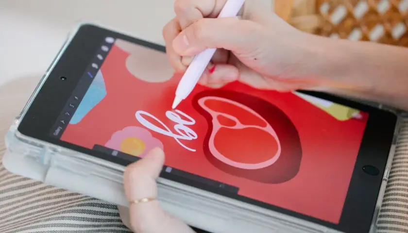 Dłoń rysuje na tablecie graficznym stylizowany stek i napis "be".