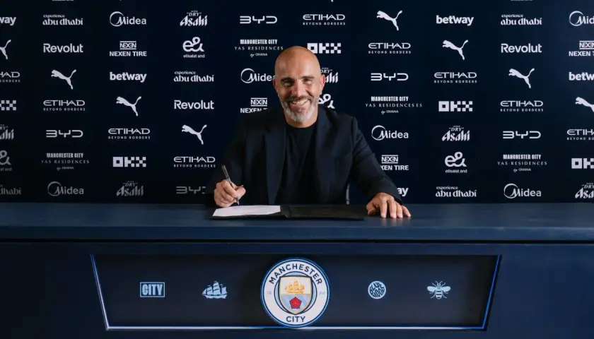 Uśmiechnięty trener Manchesteru City podpisuje kontrakt.