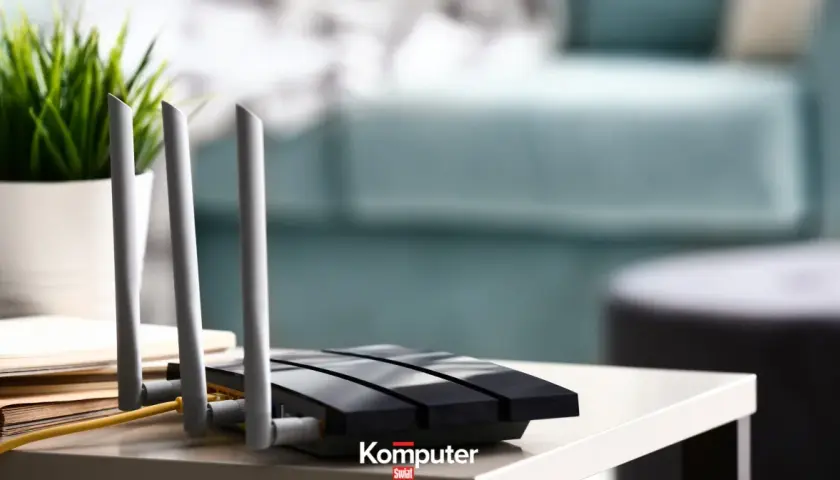 Jak podłączyć dysk do routera? Czarny router z antenkami i żółtym kablem na stoliku, obok doniczka z zieloną rośliną.