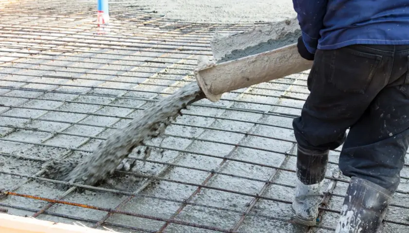 Betoniarz wylewa beton na zbrojenie, które zawiera włókna polipropylenowe, tworząc solidną posadzkę.