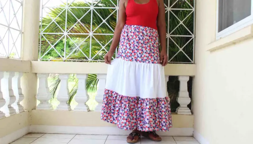 A woman models a long, tiered skirt with a colorful, mosaic-like pattern. The skirt features a white middle tier, creating a flowing, bohemian look.
