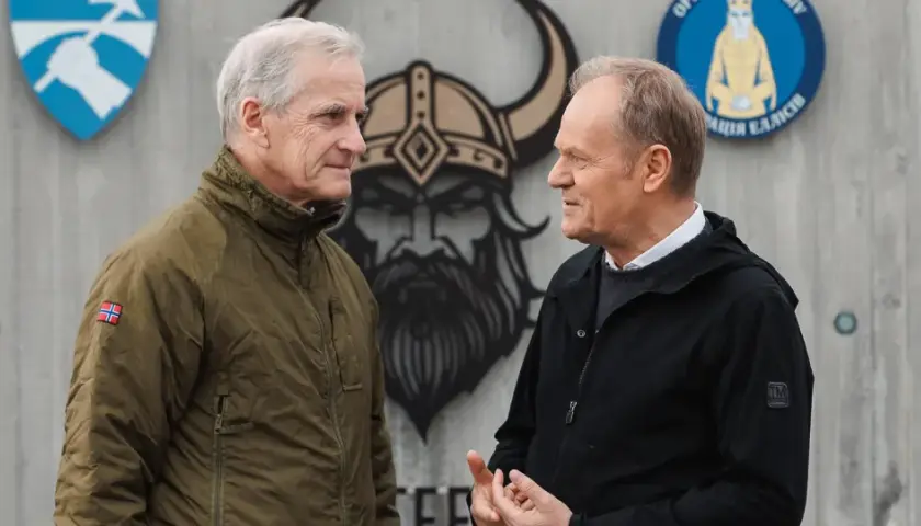 Donald Tusk i premier Norwegii rozmawiają o partnerstwie militarnym. W tle wizerunek wikinga i flagi.
