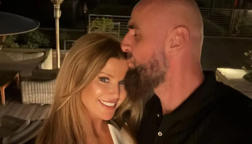 Marcin Gortat całuje swoją żonę w czoło. Para cieszy się wieczorem na tarasie.
