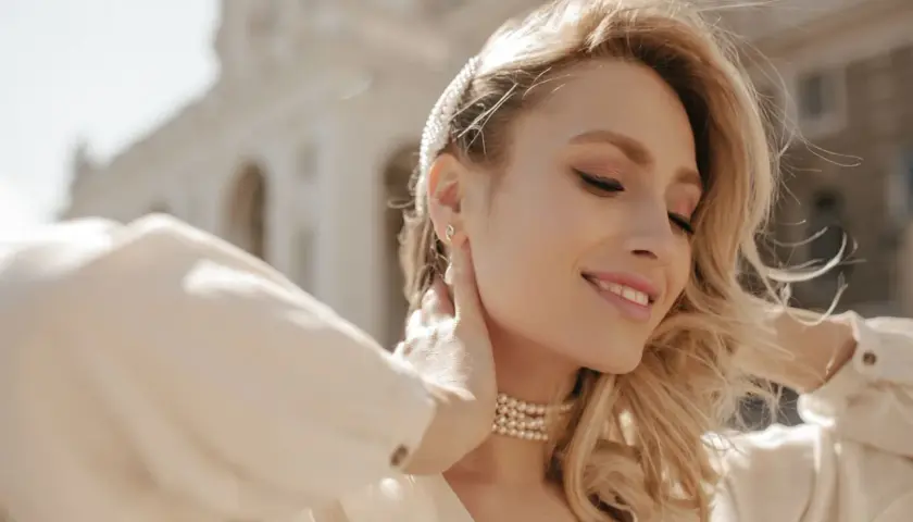 Uśmiechnięta blondynka z perłowym naszyjnikiem. Rozmiar naszyjnika idealnie podkreśla jej szyję.