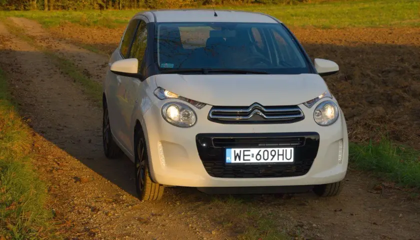 Biały Citroen C1 na tle jesiennego krajobrazu, na drodze gruntowej.