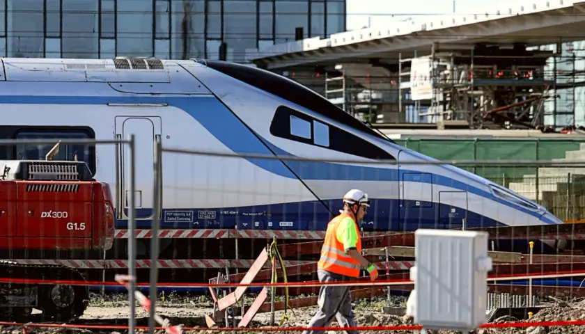 Budowa stacji, pracownik w kamizelce odblaskowej przechodzi obok pociągu Pendolino. Ile jedzie pociąg z Krakowa do Kołobrzegu?