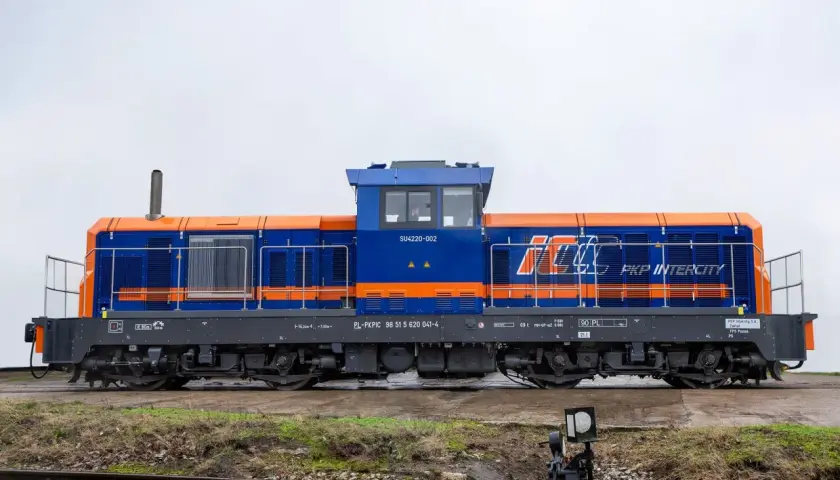 Niebiesko-pomarańczowa lokomotywa SM42 PKP Intercity SU4220-002 stoi na torach.