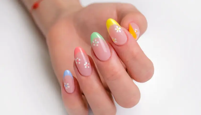 Kolorowy french manicure z uroczymi kwiatkami na paznokciach.