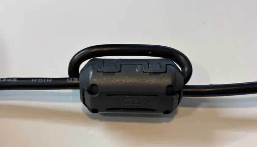 Czarny kabel z nawiniętym na niego ferrytem TDK.