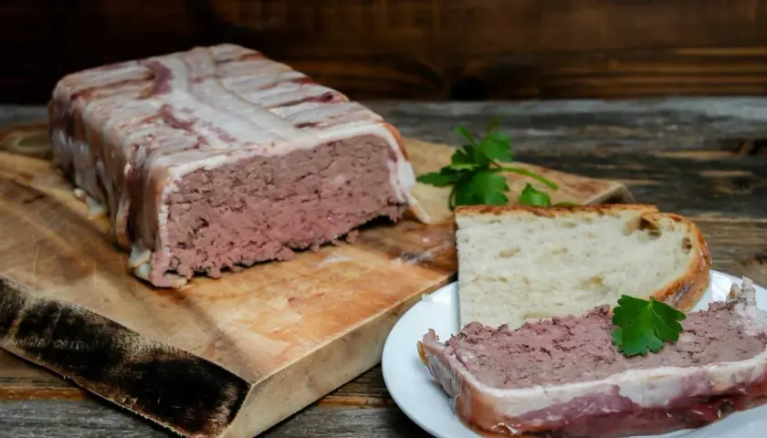 Pate zawinięte w boczek, pokrojone na talerzyku z chlebem. Pyszne pate, idealne na przekąskę.