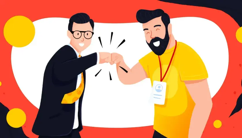 Dwóch mężczyzn w garniturze i żółtej koszulce wykonuje "fist bump" na tle czerwono-białym z żółtymi kołami.