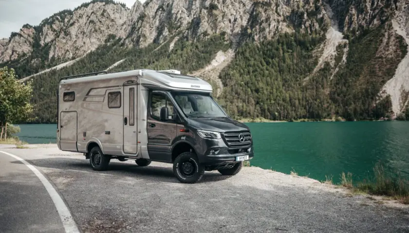 Kamper Hymer na tle gór i jeziora. Zastanawiasz się, jakie prawo jazdy na kampera jest potrzebne, by wyruszyć w taką podróż?