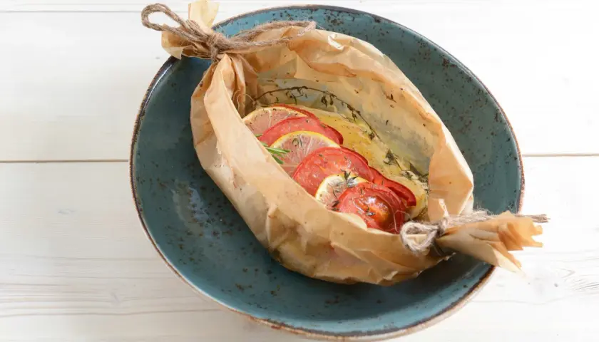Bar au barbecue en papillote, garni de rondelles de tomates et de citron, prêt à être dégusté.