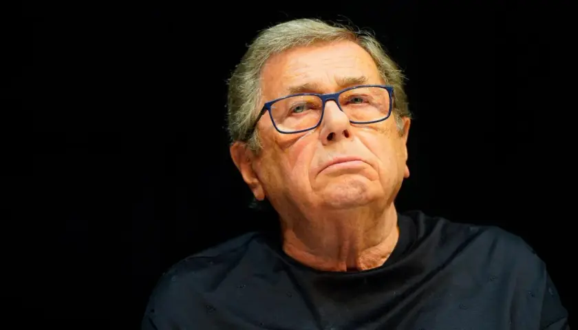 Portret Janusza Gajosa w okularach na czarnym tle.
