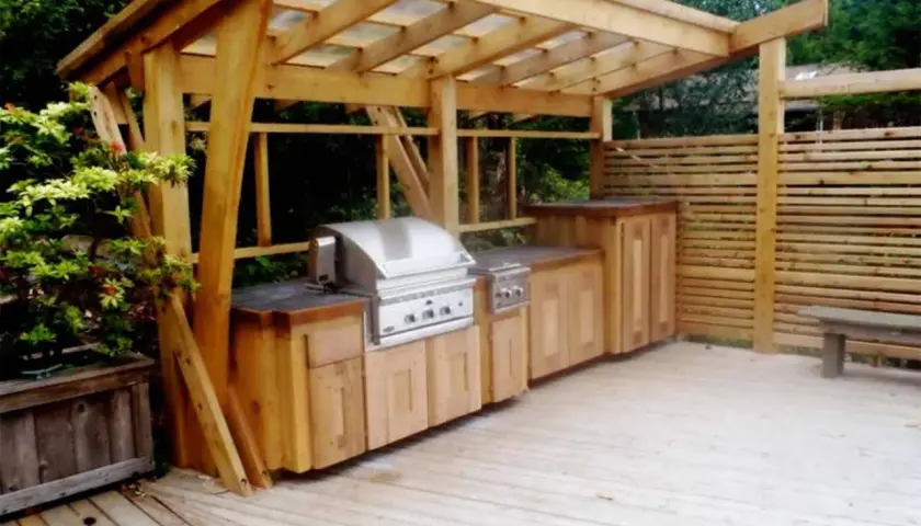En vacker murad grillplats med inbyggd grill och förvaring under ett träskydd. Perfekt för sommarens middagar utomhus.