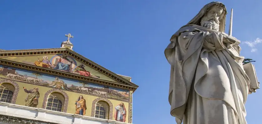 Statua imponente e facciata decorata con mosaici a San Paolo fuori le Mura. Curiosità: ogni mosaico racconta una storia biblica.