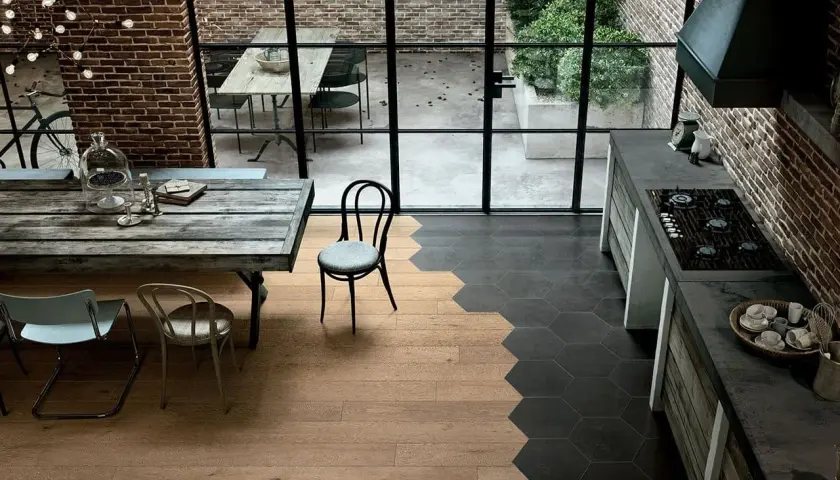 Un'elegante cucina con pavimenti che uniscono il calore del **parquet** e il design moderno delle **maioliche** esagonali scure.