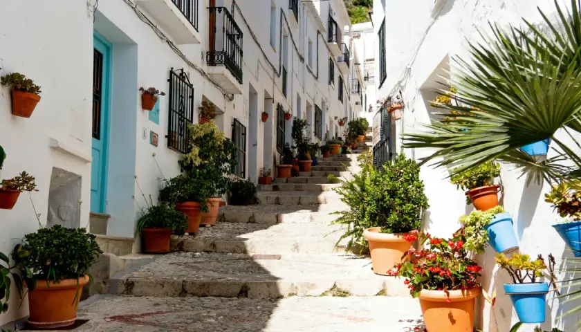 Calle empedrada con escaleras y casas blancas adornadas con macetas. Un ejemplo de los pueblos bonitos cerca de Vera.