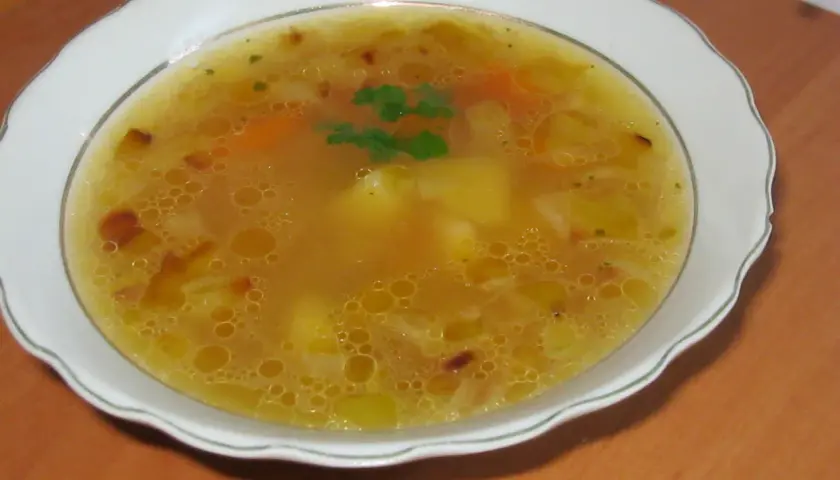 Prosta zupa cebulowa z ziemniakami, z dodatkiem marchewki i ziół, podana w białej misce.