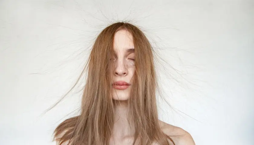 Frau mit langen Haaren, die elektrisch aufgeladen abstehen.