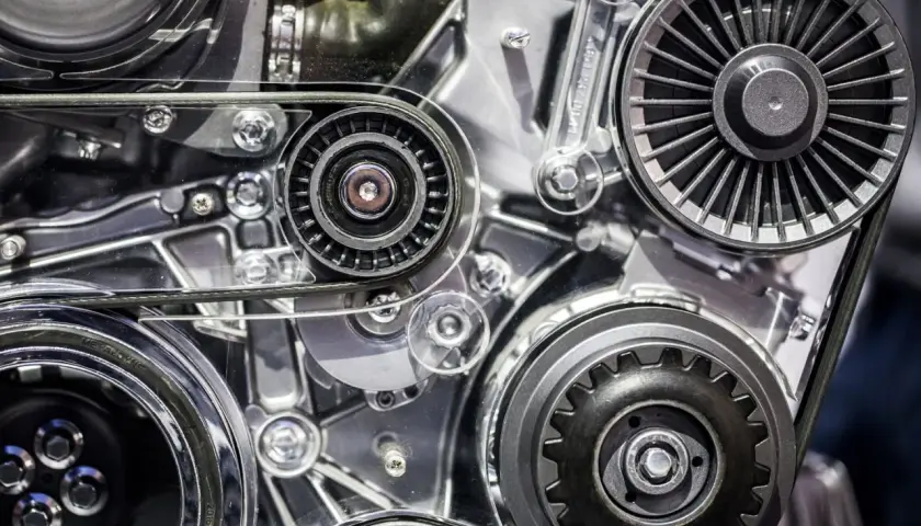 Zbliżenie na mechanizm silnika samochodowego z paskami i kołami pasowymi.