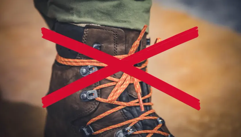 A red X crosses over a brown hiking boot with orange laces. The question "why are boot laces so long?" is implied.