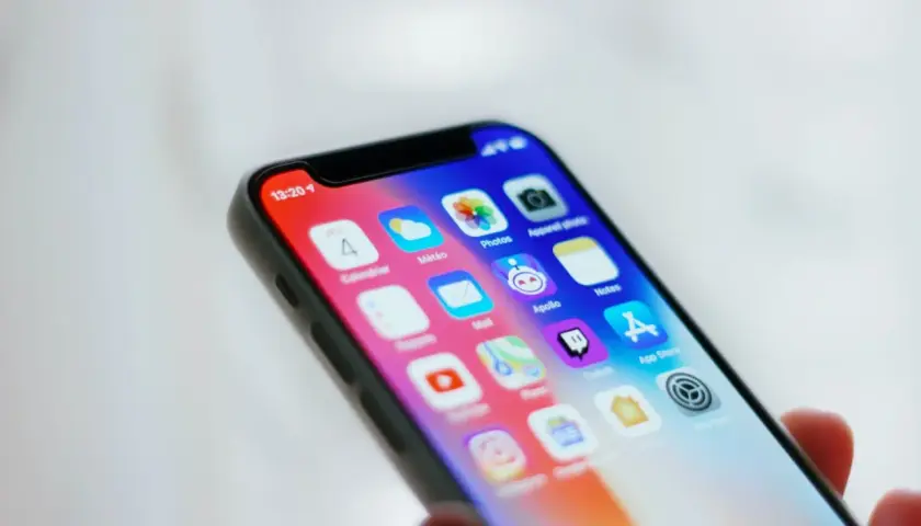 Zbliżenie na ekran smartfona z widocznymi ikonami przydatnych aplikacji, takich jak Kalendarz, Pogoda, Zdjęcia, Notatki i App Store.