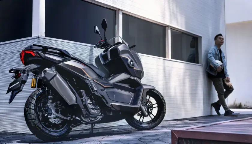 Un hombre apoya su casco en una moto moderna, lista para la aventura. La ficha técnica de esta moto promete potencia y estilo.