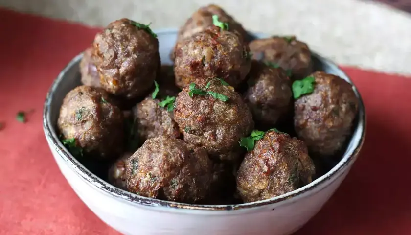 Succulente polpette in friggitrice ad aria, dorate e profumate, guarnite con prezzemolo fresco.