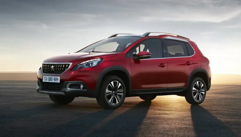 Czerwony Peugeot 2008 na tle zachodzącego słońca. Wiele osób szuka peugeot 2008 opinie przed zakupem.