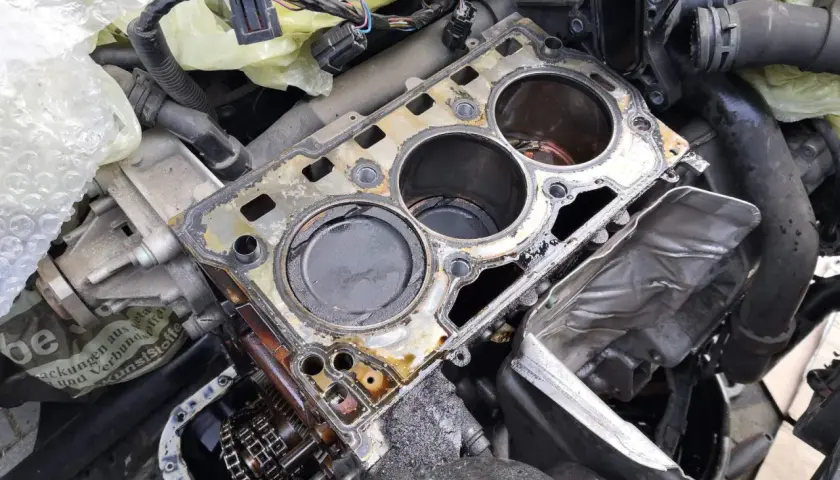 Volkswagen Motor mit defekter Zylinderkopfdichtung, wahrscheinlich DTC P0301. Öl und Schmutz sind sichtbar.