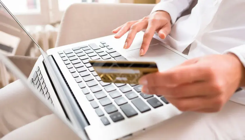 Kobieta wpisuje numer BIC karty kredytowej na laptopie, dokonując płatności online.