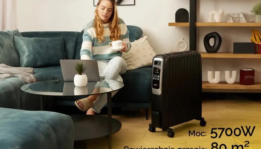 Kobieta z laptopem i kawą obok grzejnika olejowego. Sprawdź, ile prądu bierze grzejnik olejowy o mocy 5700W, ogrzewający 80 m².