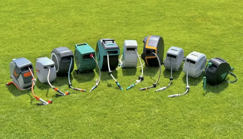 Reihe von schlauchaufroller garten Modellen in verschiedenen Farben und Designs, auf grünem Rasen arrangiert.